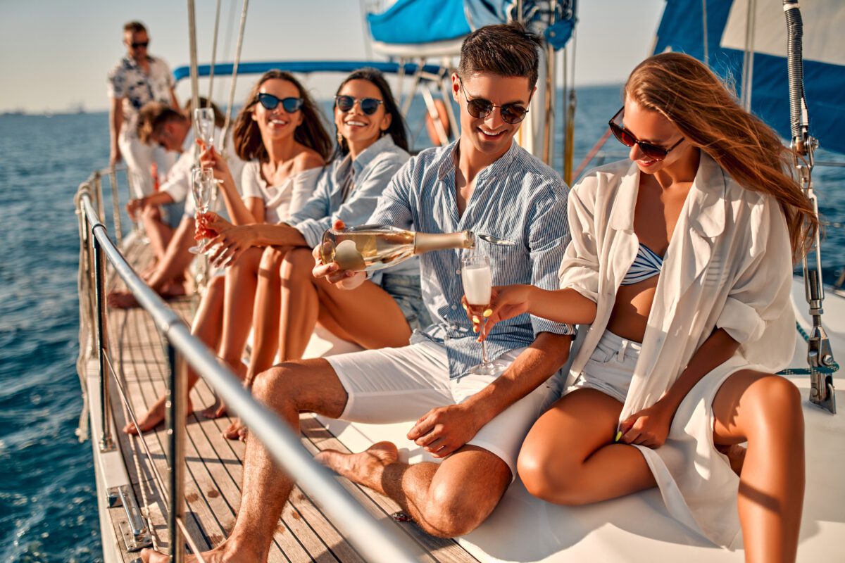 Group of friends relaxing on luxury yacht and drinking champagne. Having fun together while sailing in the sea. Traveling and yachting BRAIN Yachting